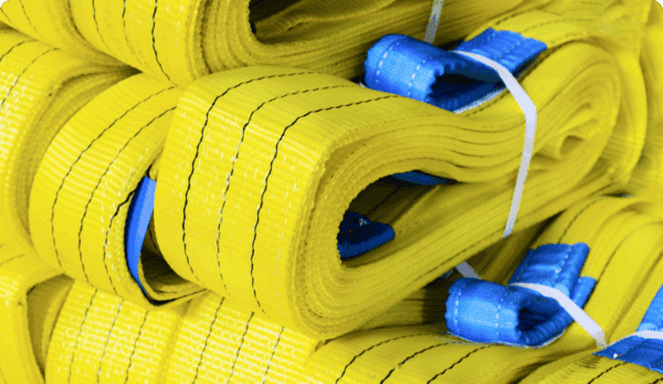 A pile of rolled yellow flat lifting straps with blue reinforced ends, secured with white ties.