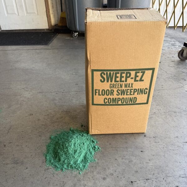 Box labeled Sweep-E-Z Pet Door Sweeping Compound with green sweeping compound on the floor.
