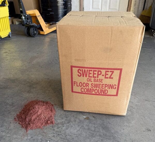 Box of Sweep-EZ floor sweeping compound with a pile spilled beside it.